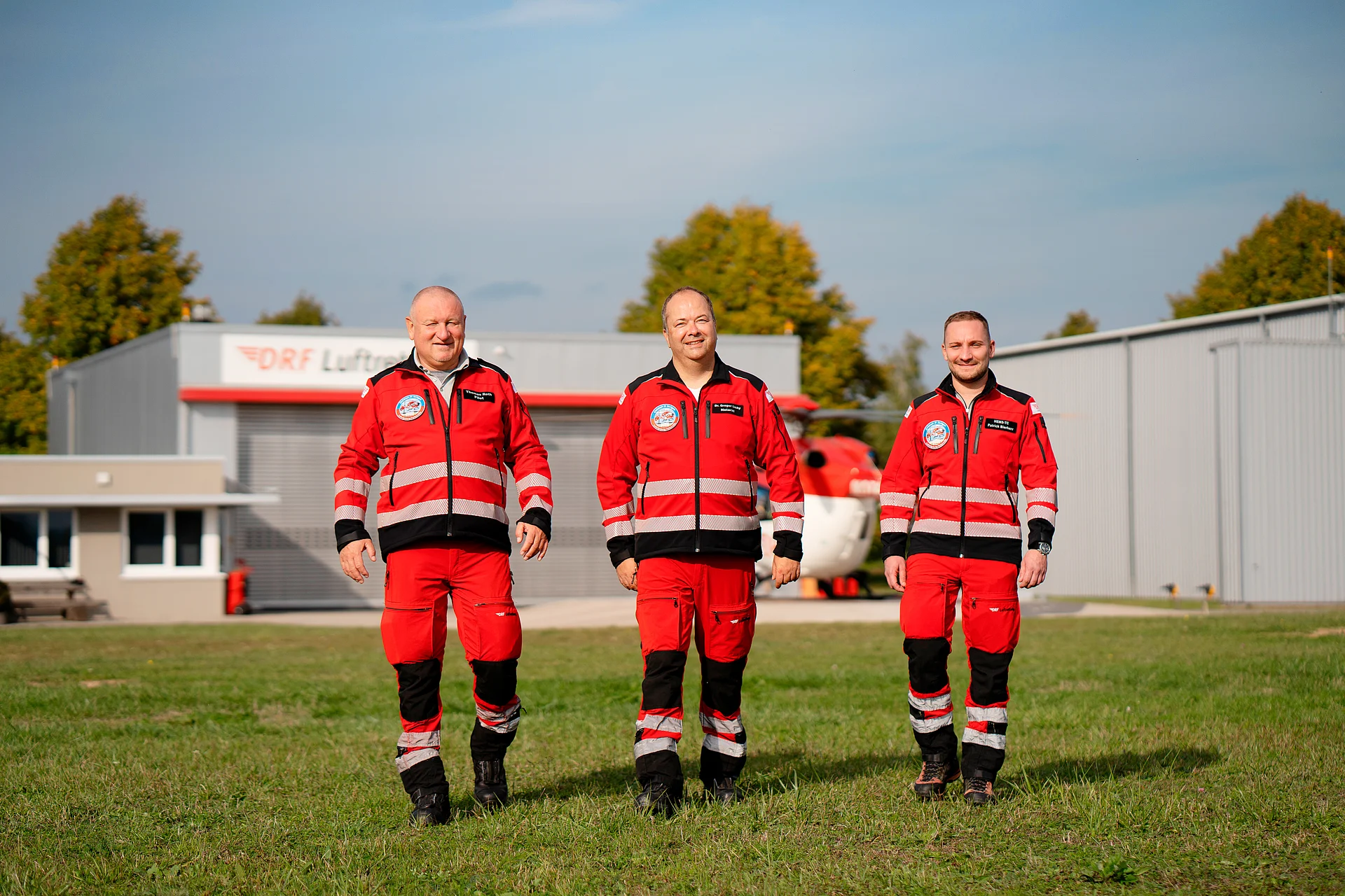 Eine Einsatzcrew läuft gemeinsam vom rot-weißen Rettungshubschrauber weg.