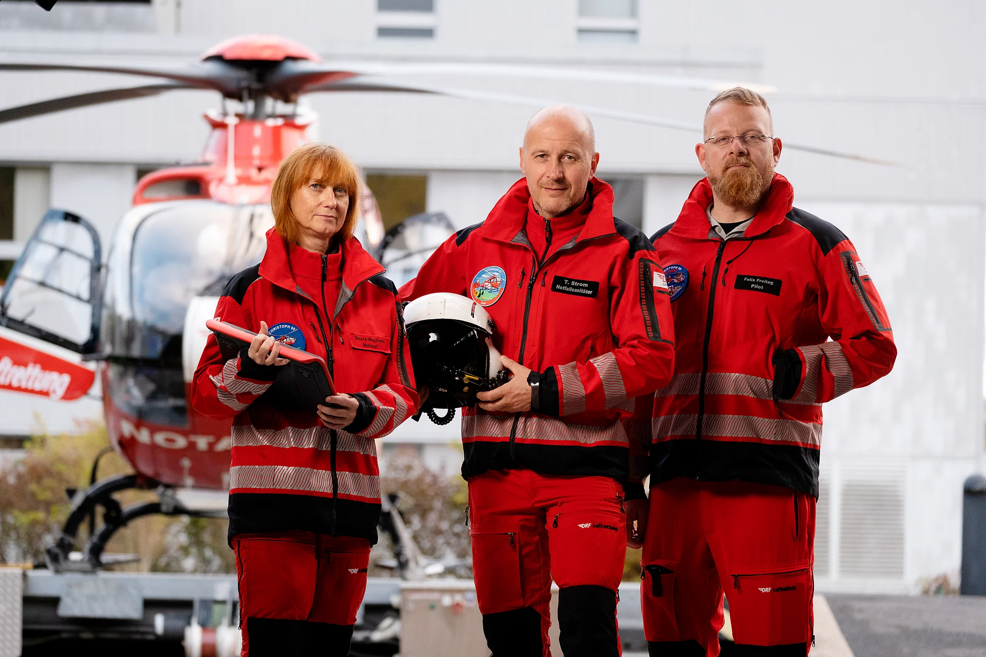 Ein rot-weißer Rettungshubschrauber steht vor dem Hangar.